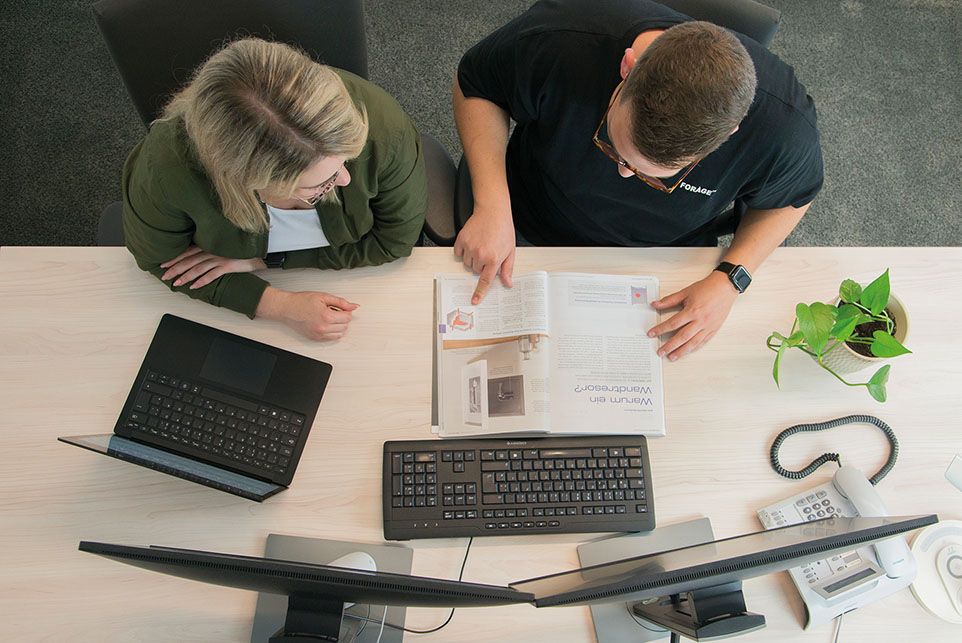 Bild von oben auf zwei Personen, die am Schreibtisch arbeiten