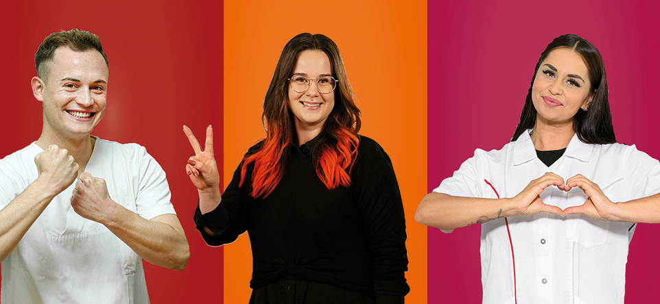Ein junger Mann und zwei junge Frauen die mit Ihren Händen Gesten zeigen zum Beispiel ein Herz und das Victory-Zeichen. Alle drei stehen vor farbigen Hintergrund: rot, orange, fuchsia