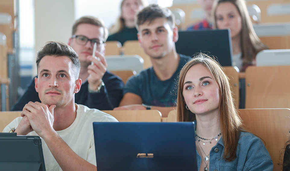 Personen im Hörsaal mit ihren Laptops.