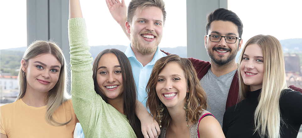 6 junge Menschen die fröhlich in die Kamera schauen