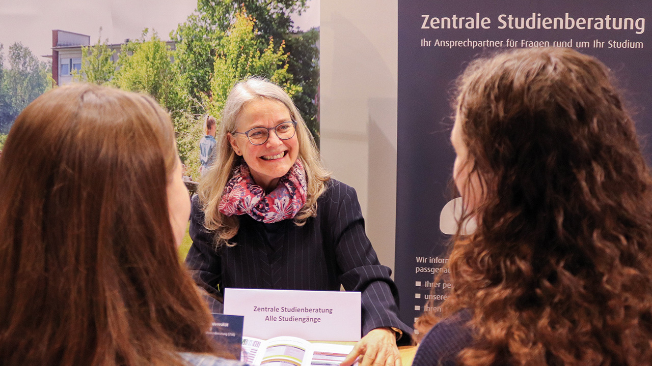 Beratung am Messestand der Studienberatung der Universität Flensburg, 3 Personen in Beratungssituation