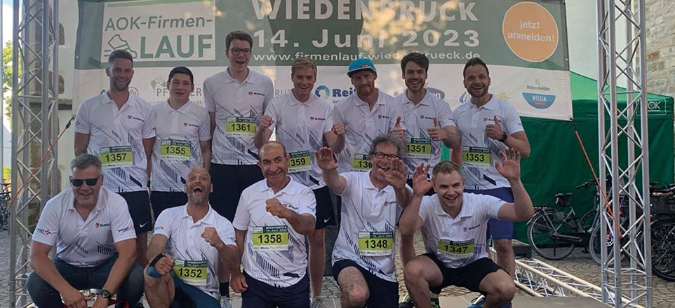 Personengruppe im Sportoutfit im Hintergrund ein Banner des AOK-Firmen-LAUF.