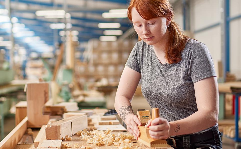 Junge Frau beim Arbeiten mit Hobel