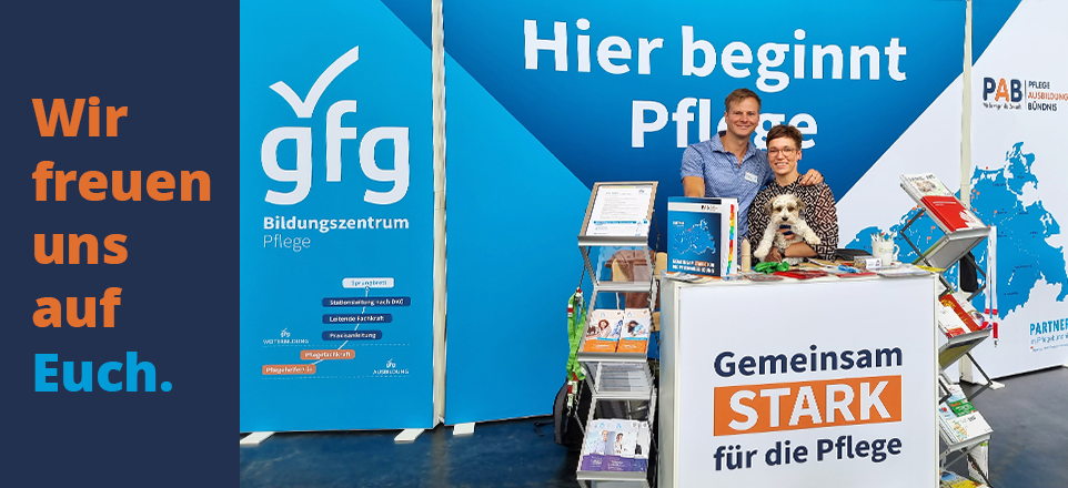 Zu sehen sind zwei Personen vor einem Messestand. 