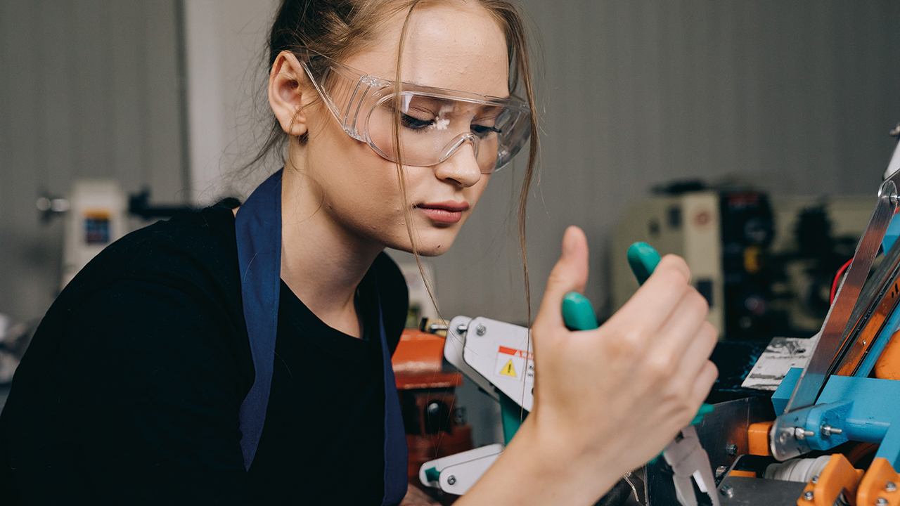 Person mit Schutzbrille arbeitet mit Werkzeug