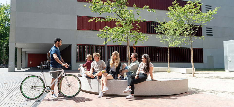 Personengruppe auf einer Sitzgelegenheit vor der Hochschule.