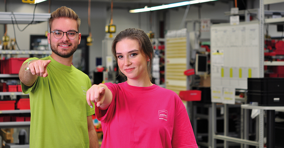 zwei Menschen in bunten shirts zeigen in richtung kamera