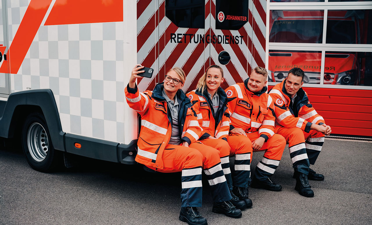 Rettungssanitäter machen ein Selfie vor einem Johanniterauto