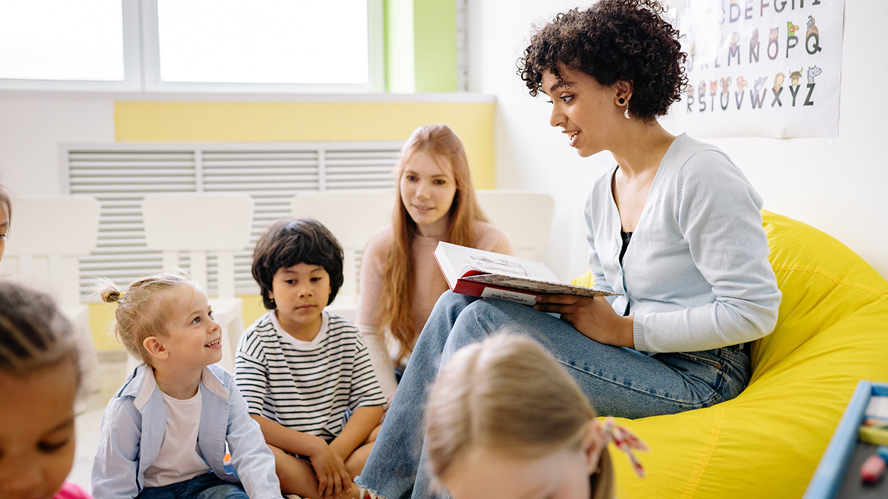 Erzieherin liest Kindern aus einem Buch vor