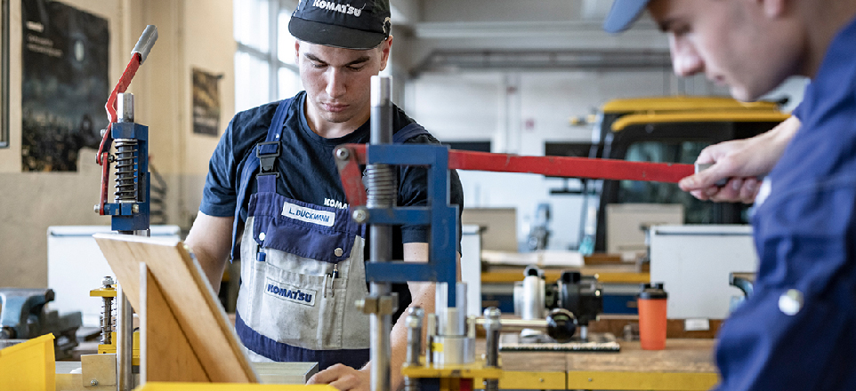 Zwei Personen in einer Werkshalle arbeiten mit Holz.