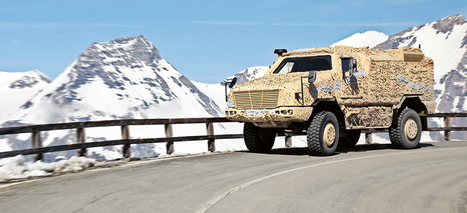 Offroadtruck auf einer Straße. Im Hintergrund sind verschneite Berge zu sehen