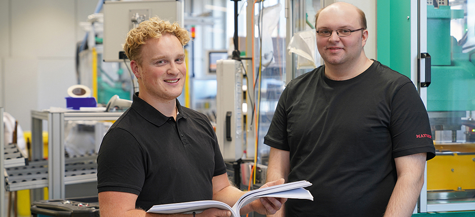 Zwei junge Menschen blättern in einem Buch in der Produktionsstätte