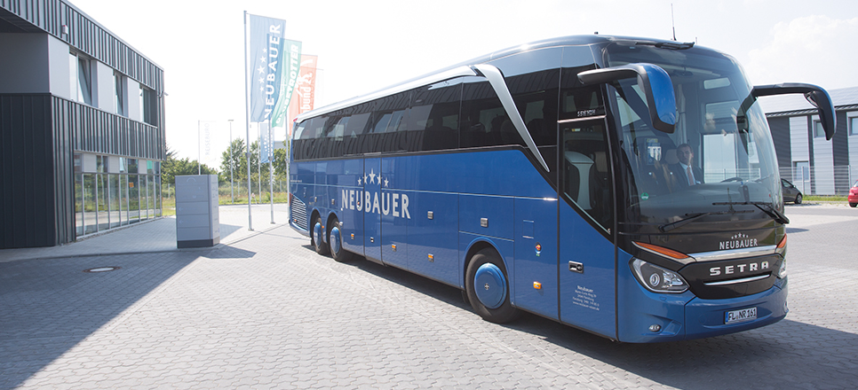 Ein blauer Reisebus der Neubauer Touristik GmbH steht vor dem Firmengebäude