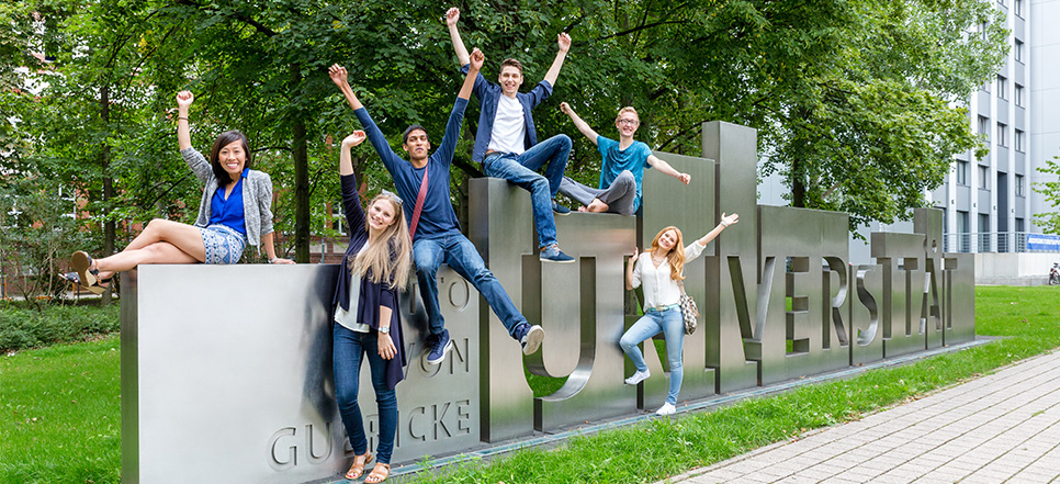 Studenten sitzen auf einem großen silber Schiftzug der Uni