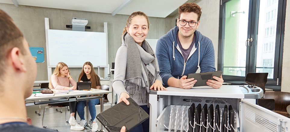 Personen in einem Klassenraum. 