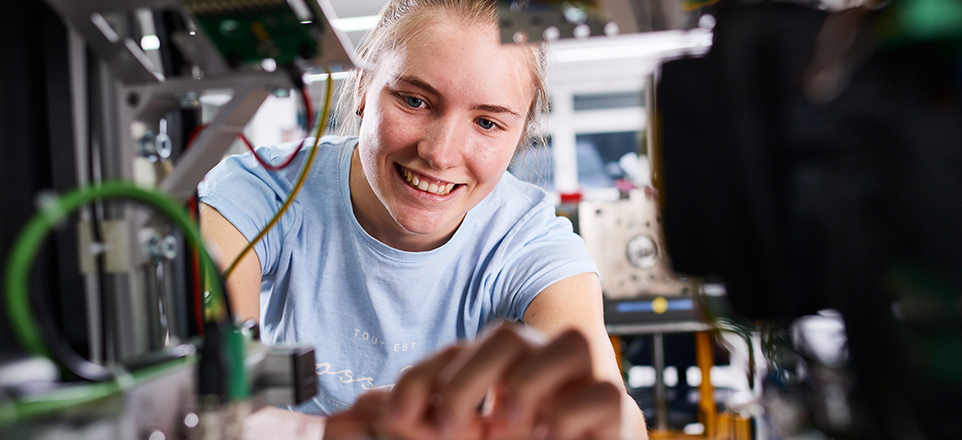 Person arbeitet an elektrischen Kabeln und lächelt.