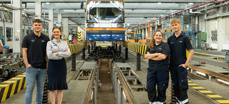 4 Personen stehen in einer Werkshalle