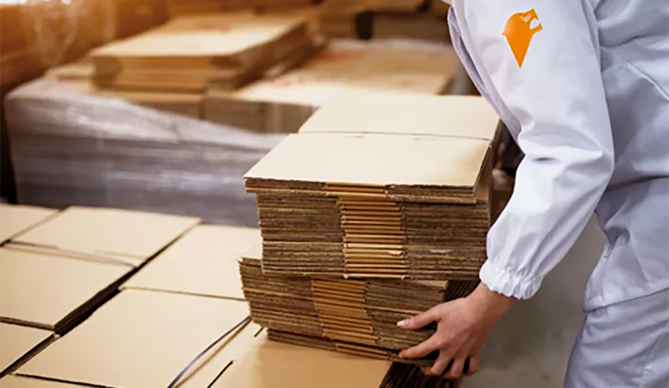 Person stapelt Wellkarton auf Palette
