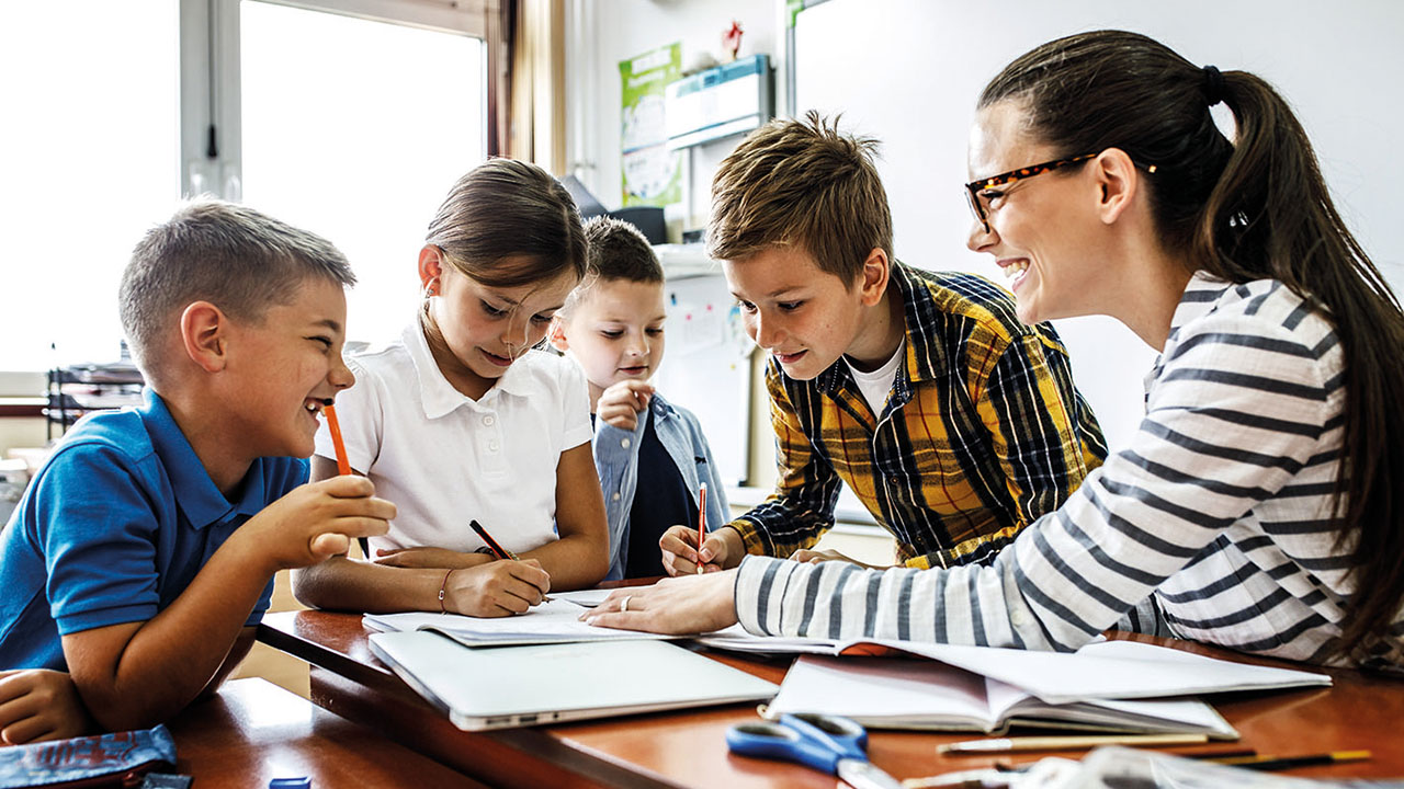 Eine erwachsene Person und vier Kinder sitzen im Kreis, lächeln und malen.