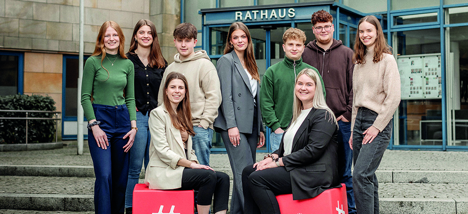 Gruppenfoto von neun Auszubildenden vor dem Rathaus