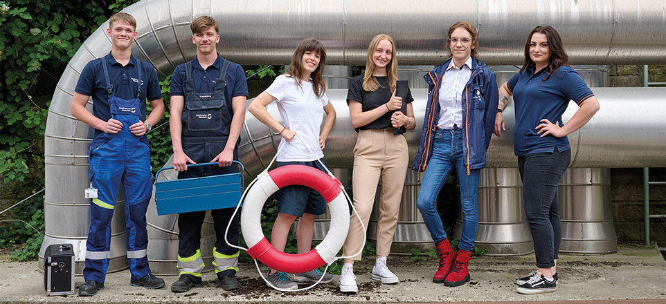 Personengruppe vor mehreren Rohren.