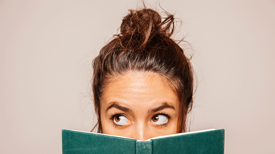 Junge Frau hinter einem Buch (Symbolbild). Bild von Freepik.